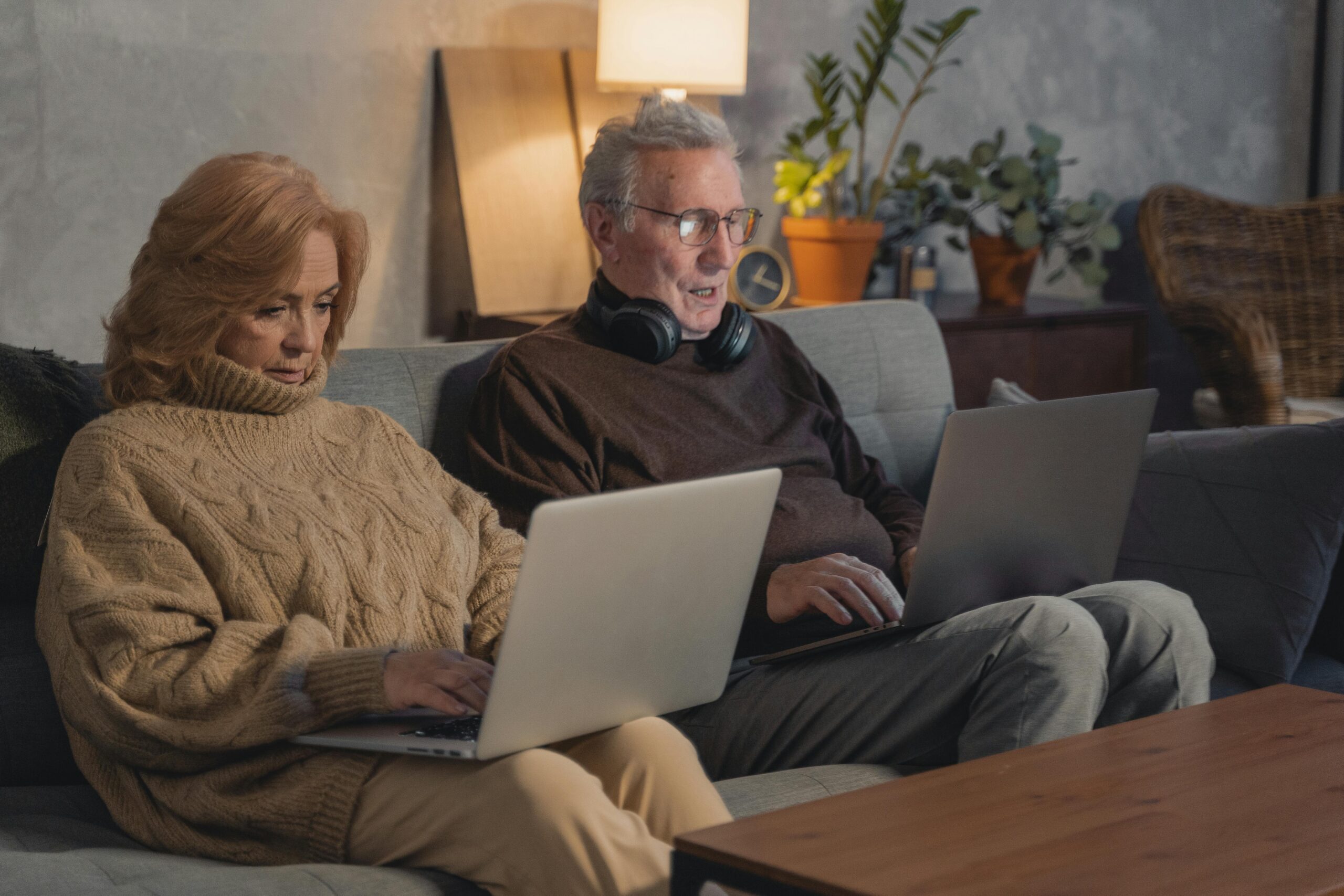 Man and Woman Sitting on Couch Using Macbook